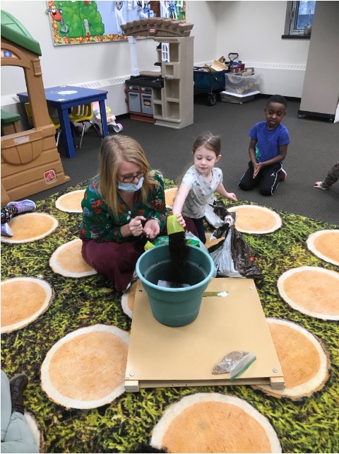 A girl filling a flowerpot with soil at SCA