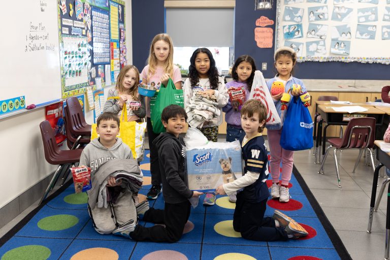 Students holding up items to donate to a pet shelter