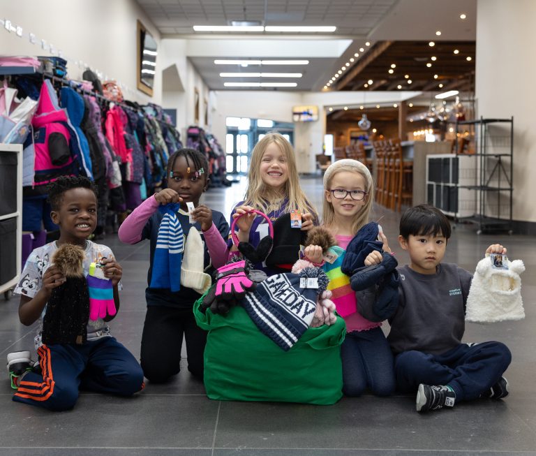 Students holding up mitts and toques